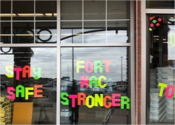 « Fort Mac Stronger Together » et « Stay Safe » écrits en lettres colorées dans les fenêtres d’un magasin. 