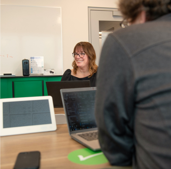 In this image, a woman discusses something with the team and laughs.