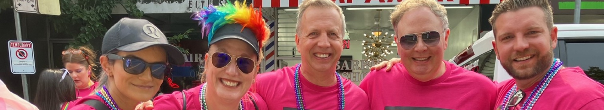 In this image, some people dressed in pink clothes are smiling while taking their pictures.