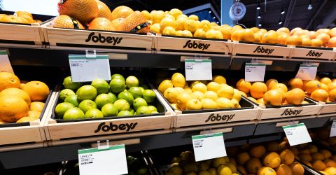 A grocery store display with wooden bins labeled "Sobeys," holding a variety of citrus fruits including oranges, lemons, and limes.