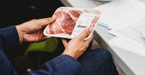 In this picture, a man is holding chicken packaging in his hands.